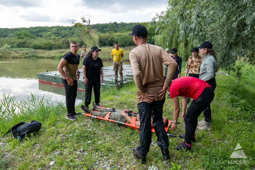 Leadership School participants preparing equipment together beside a lake during an outdoor challenge